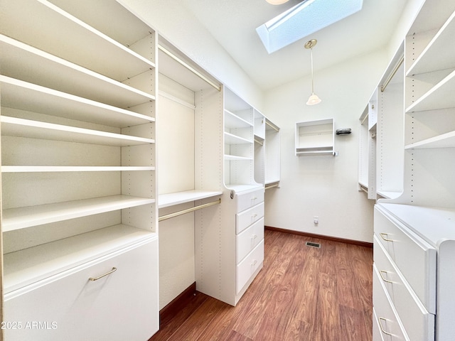 walk in closet featuring wood finished floors and a skylight