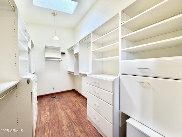 walk in closet with visible vents, a skylight, and wood finished floors