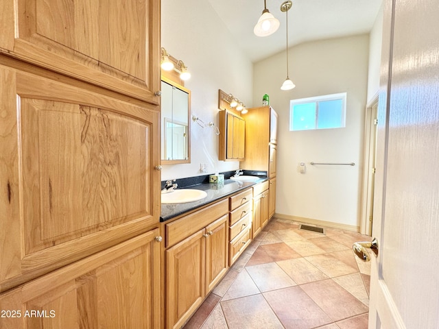 full bath with tile patterned flooring, lofted ceiling, double vanity, and a sink