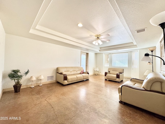 living area with baseboards, visible vents, a textured ceiling, and a tray ceiling