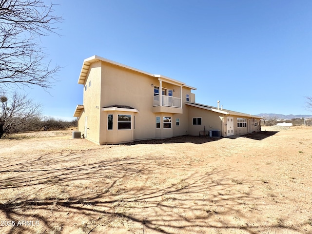 back of property with stucco siding, cooling unit, and a balcony