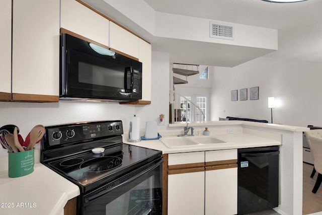 2333 E Southern Ave Unit 2016, Tempe, AZ 85282 - kitchen with black appliances, light countertops, white cabinetry, a peninsula, and open floor plan