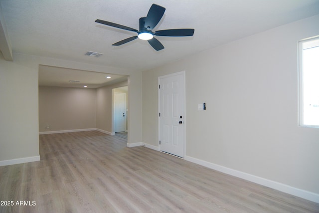 empty room featuring light wood-type flooring, visible vents, ceiling fan, and baseboards