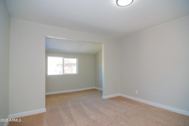 empty room featuring light carpet and baseboards