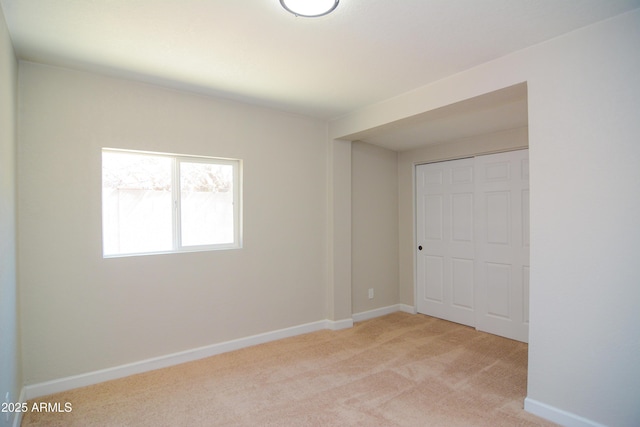 unfurnished bedroom featuring baseboards, a closet, and light colored carpet