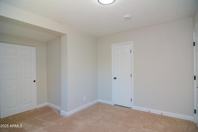 unfurnished room with baseboards and light colored carpet