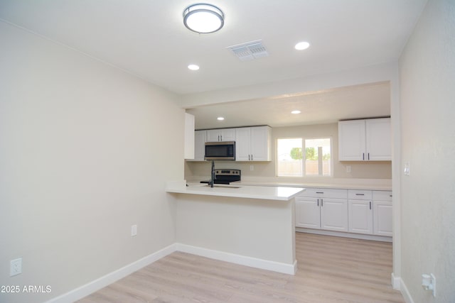 kitchen featuring visible vents, baseboards, light wood-style floors, white cabinetry, and appliances with stainless steel finishes