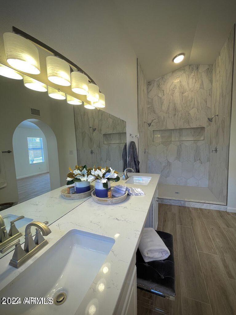 bathroom with tiled shower and vanity