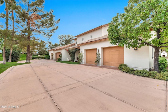 mediterranean / spanish home featuring stucco siding, a tiled roof, and concrete driveway