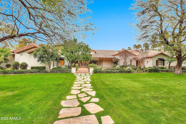 view of front of house with stucco siding, a tiled roof, and a front lawn