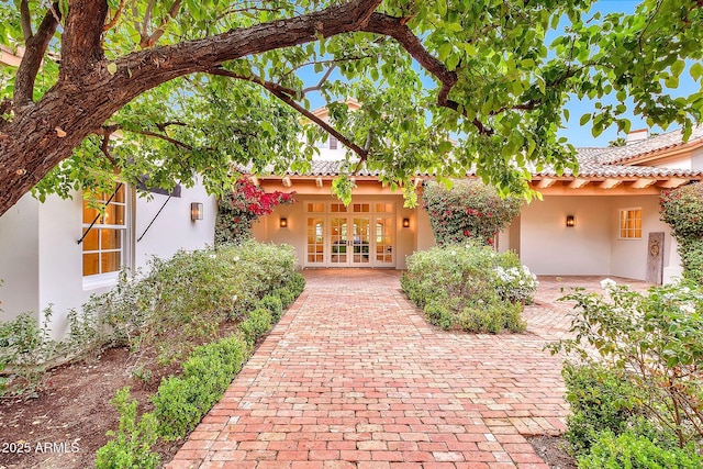 exterior space featuring a tiled roof, stucco siding, and french doors