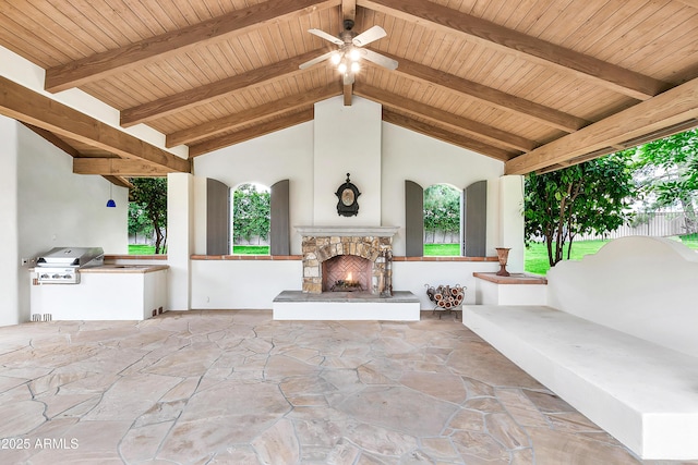 view of patio with area for grilling, a grill, a ceiling fan, and an outdoor stone fireplace