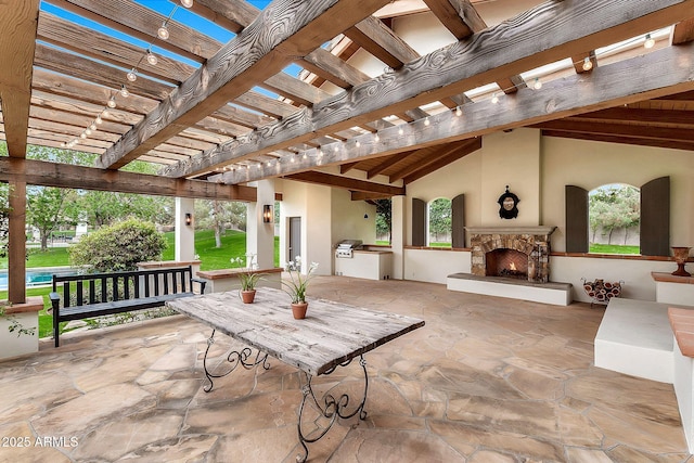 view of patio with exterior kitchen, a pergola, and an outdoor stone fireplace