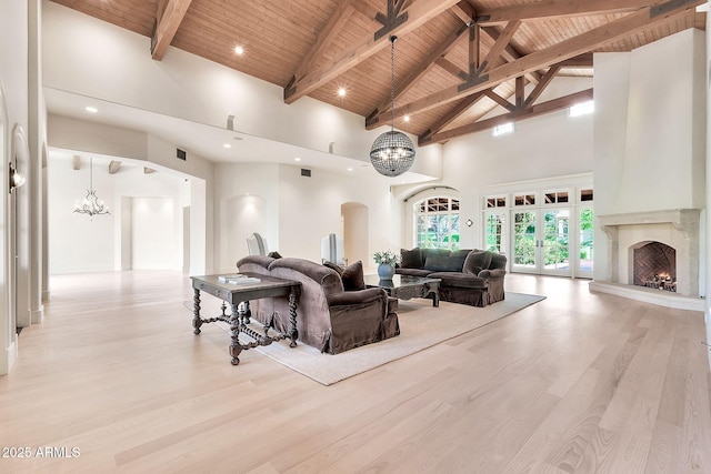 living room with arched walkways, wood ceiling, light wood-style floors, beamed ceiling, and a chandelier