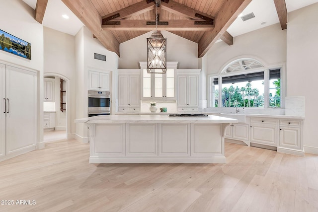 kitchen featuring beam ceiling, light wood-style flooring, a center island, and stainless steel appliances