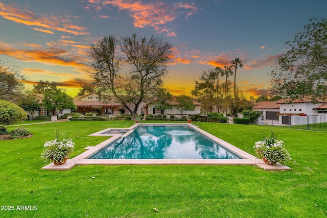 pool at dusk featuring a yard and an outdoor pool