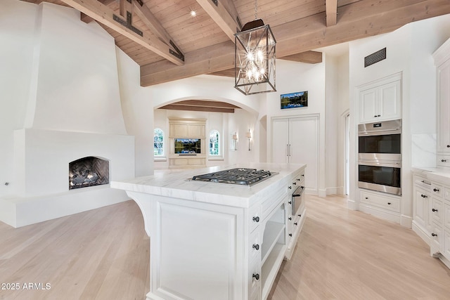 kitchen with visible vents, a center island, wood ceiling, appliances with stainless steel finishes, and arched walkways