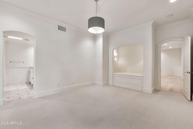 unfurnished room with visible vents, light carpet, arched walkways, crown molding, and baseboards