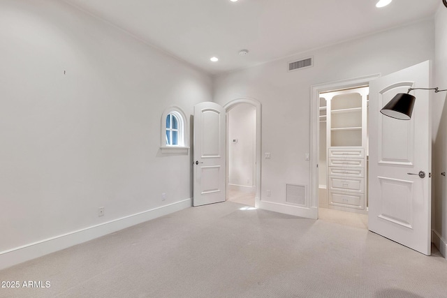 unfurnished bedroom featuring a walk in closet, recessed lighting, visible vents, and baseboards