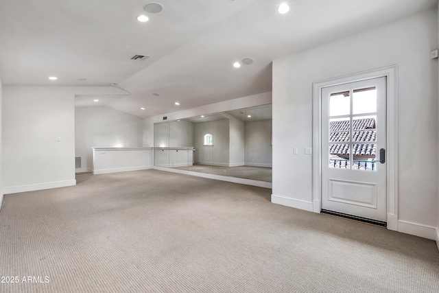 empty room featuring carpet flooring, recessed lighting, visible vents, and vaulted ceiling