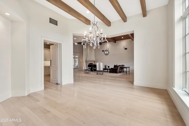 unfurnished dining area featuring an inviting chandelier, light wood-style flooring, beamed ceiling, and visible vents