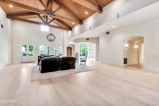 living area with visible vents, a notable chandelier, light wood-style flooring, arched walkways, and wooden ceiling
