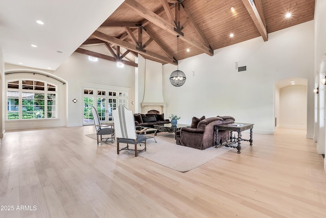 living area featuring light wood finished floors, high vaulted ceiling, arched walkways, wood ceiling, and beamed ceiling