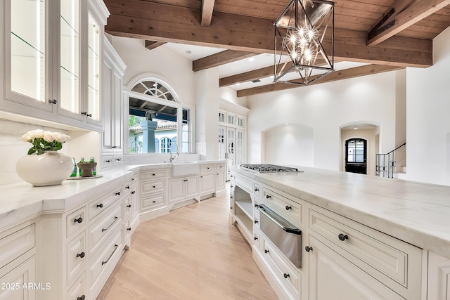 kitchen with light wood-type flooring, wooden ceiling, an inviting chandelier, arched walkways, and a warming drawer