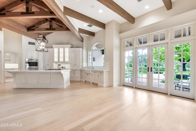 kitchen featuring high vaulted ceiling, light countertops, white cabinets, light wood-style floors, and a notable chandelier