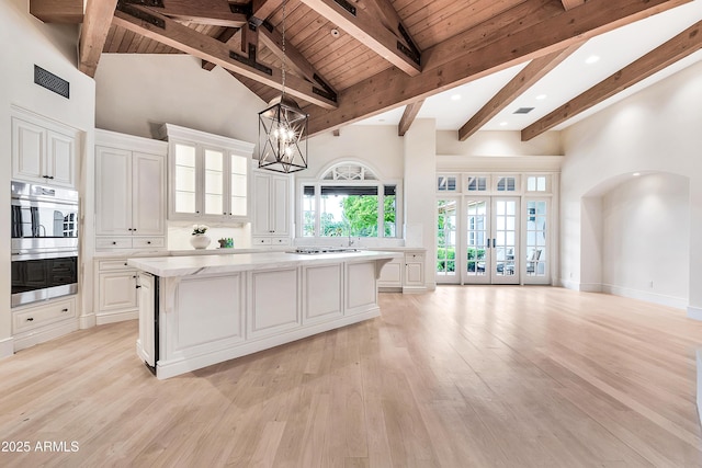 kitchen featuring light wood finished floors, visible vents, a kitchen island, stainless steel double oven, and white cabinets