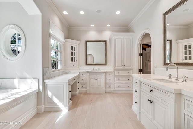 full bath featuring crown molding, two vanities, wood finished floors, and a sink