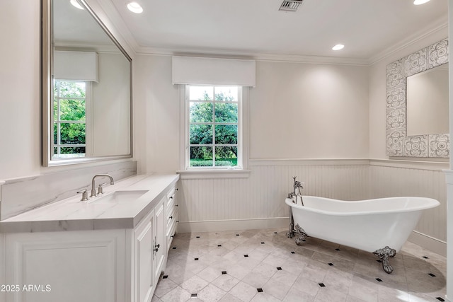 bathroom with a wainscoted wall, plenty of natural light, crown molding, and visible vents