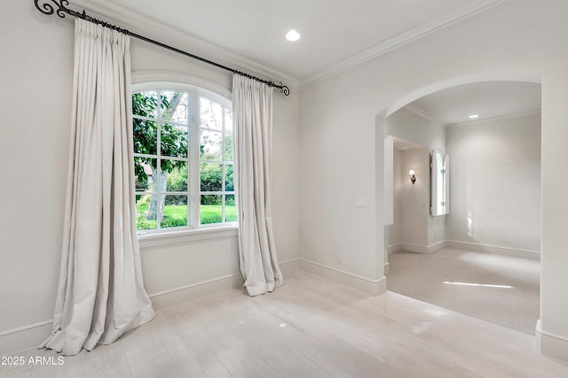 spare room featuring recessed lighting, baseboards, arched walkways, and ornamental molding