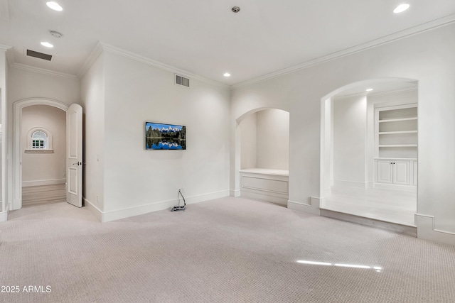 empty room featuring baseboards, visible vents, arched walkways, and light carpet