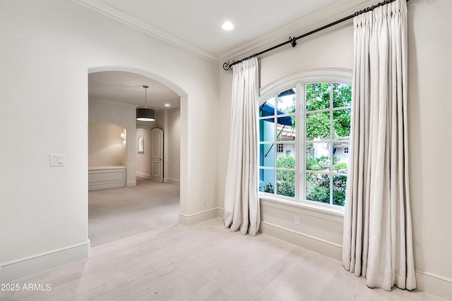 unfurnished room with crown molding, baseboards, recessed lighting, wood finished floors, and arched walkways