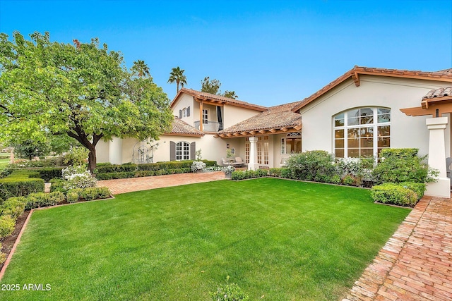 mediterranean / spanish-style house featuring stucco siding, a tiled roof, and a front yard