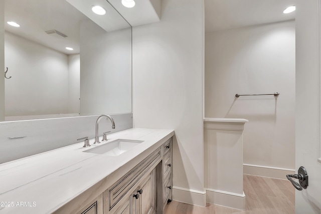 bathroom featuring vanity, wood finished floors, visible vents, baseboards, and recessed lighting