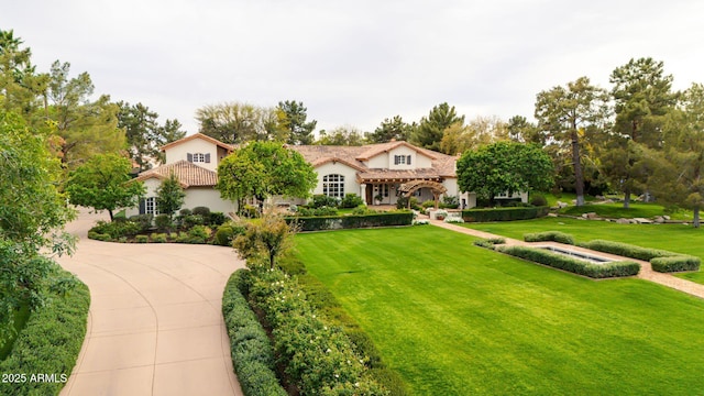 mediterranean / spanish-style home featuring a front yard, a tile roof, and stucco siding