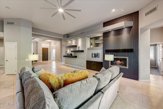 tiled living room with ceiling fan and a tile fireplace