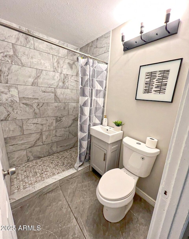 bathroom with vanity, a textured ceiling, toilet, and walk in shower