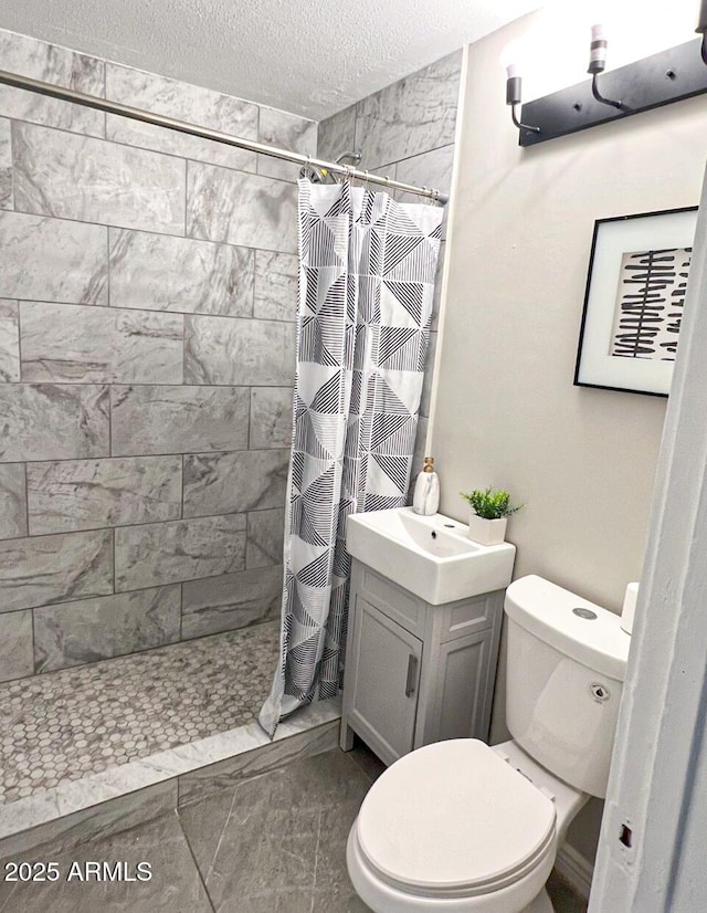 bathroom featuring a textured ceiling, vanity, toilet, and walk in shower