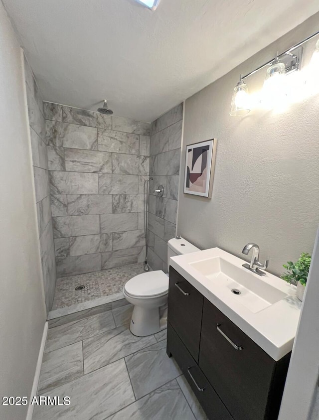 bathroom with vanity, toilet, and a tile shower