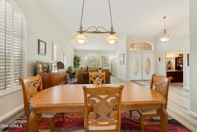 dining area with light hardwood / wood-style flooring and high vaulted ceiling