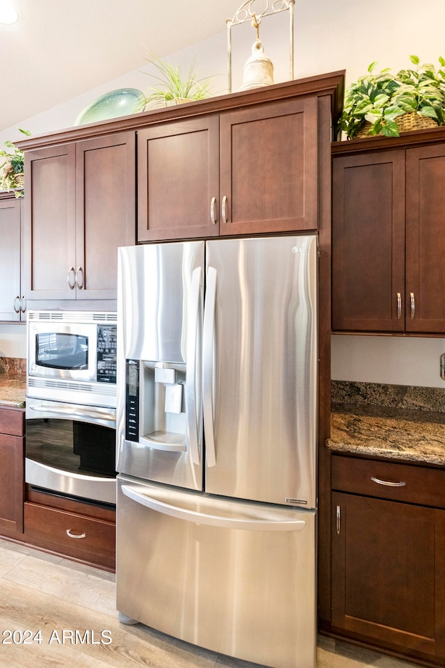 kitchen featuring light hardwood / wood-style floors, dark stone countertops, and appliances with stainless steel finishes