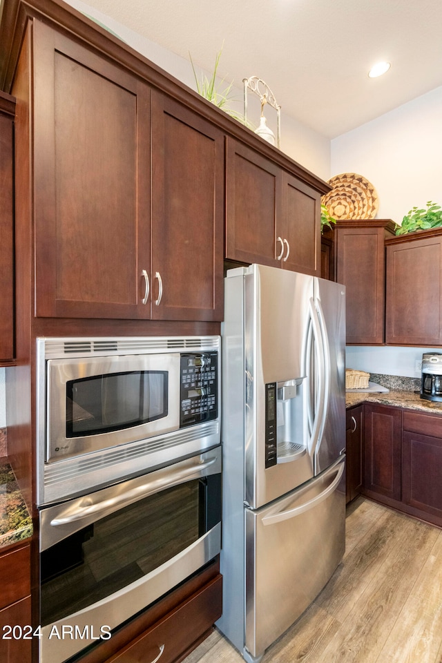 kitchen with appliances with stainless steel finishes, light stone counters, and light wood-type flooring