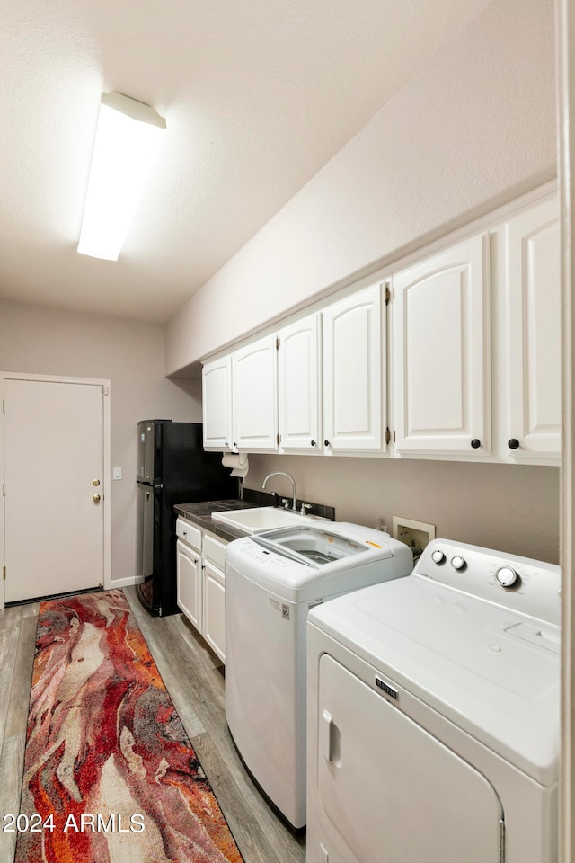 laundry room featuring sink, cabinets, washer and clothes dryer, and light wood-type flooring