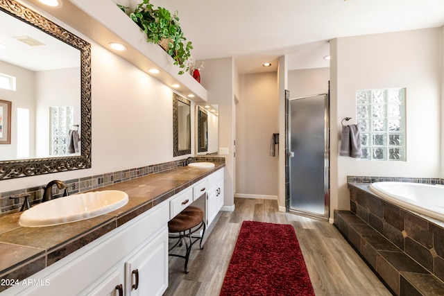 bathroom featuring shower with separate bathtub, wood-type flooring, tasteful backsplash, and dual bowl vanity