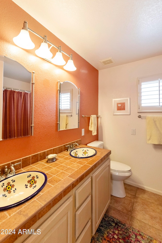 bathroom with vanity, a wealth of natural light, tile patterned flooring, and toilet