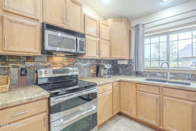 kitchen with appliances with stainless steel finishes, tasteful backsplash, a sink, and light brown cabinetry