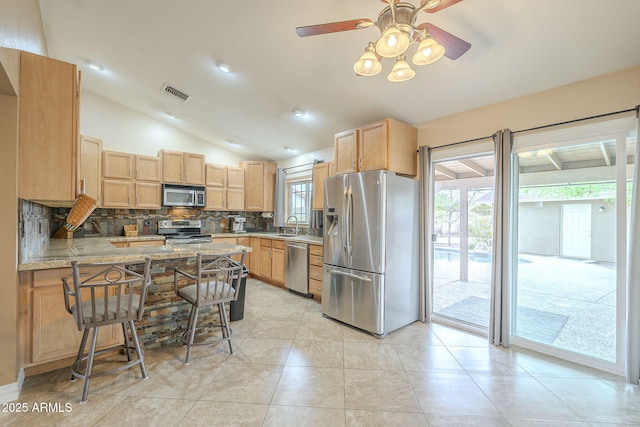 kitchen with a peninsula, visible vents, appliances with stainless steel finishes, backsplash, and light brown cabinetry